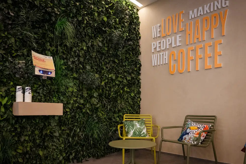 The green wall with the words “We love making people happy with coffee”.